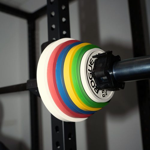Poids colorés sur une barre d'haltérophilie, symbolisant la performance chez JUX Coaching.